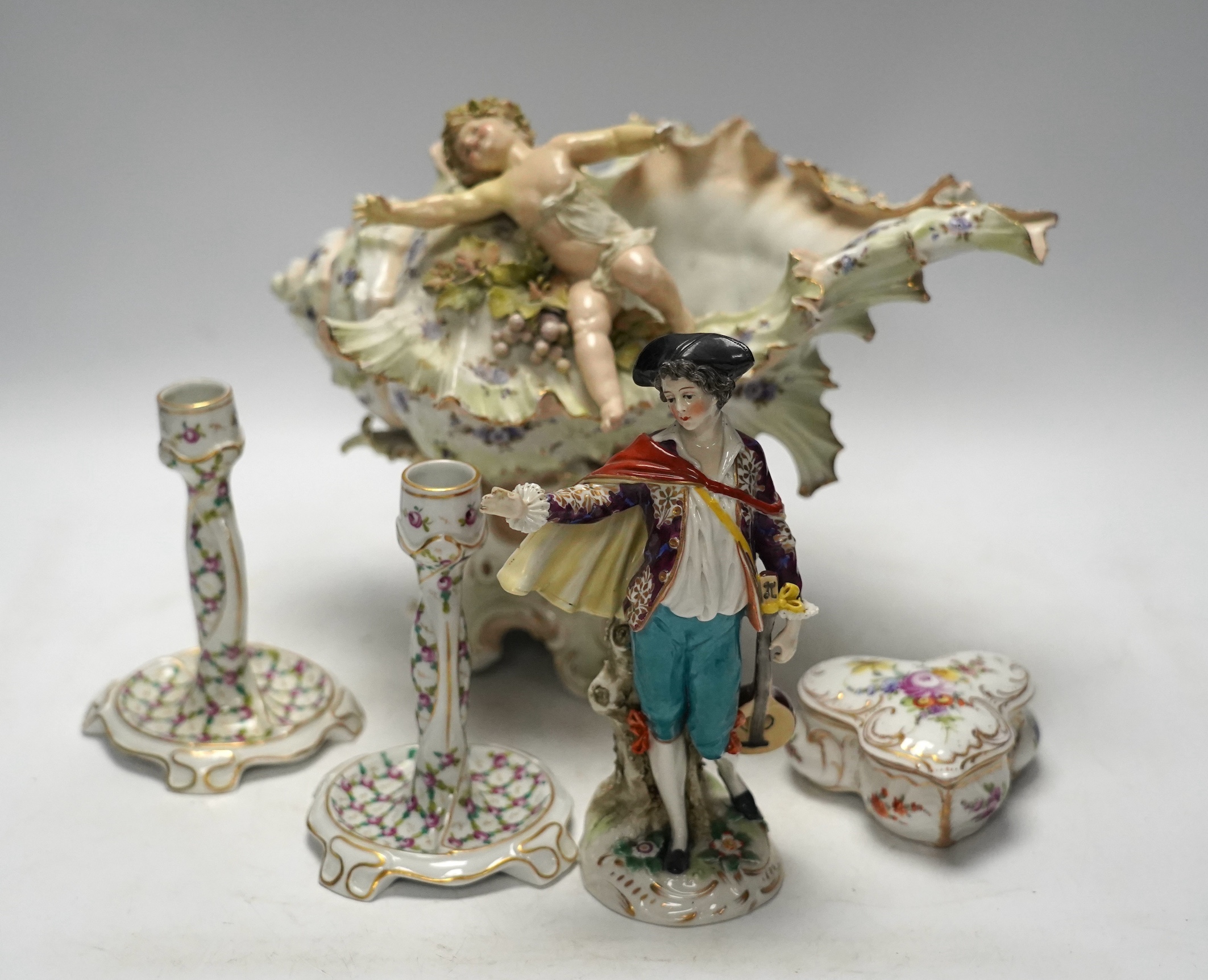 A porcelain shell-shaped centrepiece, a Dresden pill box, a pair of taper holders and a porcelain figure, tallest 21cm